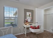 Thumbnail 16 of 23 - A room with a desk, chair, and a window with blinds.