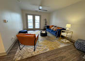 Thumbnail 4 of 19 - A living room with a blue couch and an orange chair.