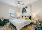 Thumbnail 6 of 62 - a bedroom with a bed and a chair and a ceiling fan at 41 North Apartments, Indiana, 46835