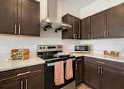 Thumbnail 37 of 62 - a kitchen with brown cabinets and stainless steel appliances and white countertops at 41 North Apartments, Fort Wayne