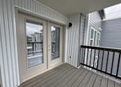 Thumbnail 11 of 19 - A balcony with a sliding door and a railing.