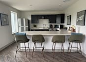 Thumbnail 1 of 19 - A kitchen with a bar area and three bar stools.