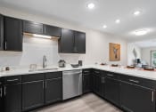 Thumbnail 32 of 43 - a large kitchen with black cabinets and white counter tops and a sink at Morada at Maysville, Fort Wayne Indiana