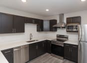 Thumbnail 1 of 43 - a kitchen with stainless steel appliances and black cabinets at Morada at Maysville, Fort Wayne, IN 46815