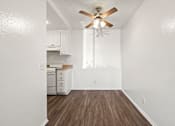 Thumbnail 33 of 40 - A white kitchen with a wood floor and a ceiling fan.