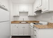 Thumbnail 31 of 40 - A white kitchen with granite countertops and white appliances.