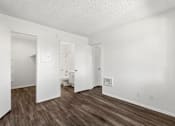 Thumbnail 37 of 40 - A white room with wood flooring and a doorway leading to another room.