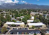 Thumbnail 9 of 40 - A parking lot with cars and a building in the foreground with a mountain in the background.