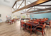 Thumbnail 21 of 40 - A large room with wooden floors and tables with chairs.