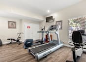 Thumbnail 26 of 40 - A home gym with a treadmill, exercise bike, and other equipment.