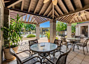 Thumbnail 18 of 40 - A patio with a table and chairs under a roof.