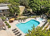 Thumbnail 14 of 40 - A large outdoor swimming pool surrounded by lounge chairs and trees.
