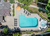 Thumbnail 16 of 40 - An aerial view of a swimming pool surrounded by a concrete patio and a small fountain.