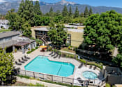 Thumbnail 13 of 40 - A large outdoor swimming pool surrounded by a fence and lounge chairs.