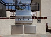 Thumbnail 10 of 50 - A silver grill is on top of a wall next to a wall-mounted fridge.