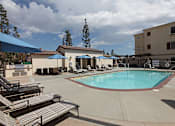 Thumbnail 7 of 50 - A pool with sun loungers and umbrellas in front of a building.