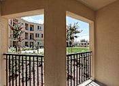 Thumbnail 26 of 50 - A balcony view of a building with a black railing and a tree in the foreground.