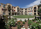 Thumbnail 1 of 50 - A large building with a courtyard surrounded by trees and flowers.