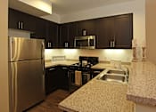 Thumbnail 29 of 50 - A kitchen with a stainless steel refrigerator and black cabinets.