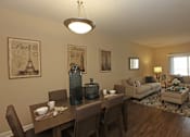 Thumbnail 36 of 50 - A dining room with a table set for two and a couch in the background.