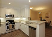 Thumbnail 34 of 50 - A kitchen with white cabinets and a wooden floor.