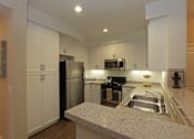 Thumbnail 32 of 50 - A kitchen with a granite counter top and stainless steel appliances.