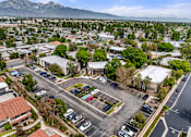 Thumbnail 3 of 30 - A parking lot with cars and buildings in the foreground with mountains in the background.