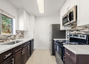 Thumbnail 4 of 35 - A kitchen with dark brown cabinets and stainless steel appliances.