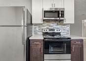 Thumbnail 6 of 35 - A modern kitchen with a stainless steel refrigerator, microwave, and oven.