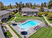 Thumbnail 23 of 35 - A swimming pool surrounded by a fence and chairs in a residential area.