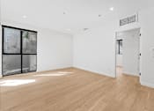 Thumbnail 63 of 119 - A room with wooden floors and a large window with a view of trees.