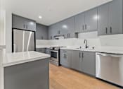 Thumbnail 90 of 119 - A modern kitchen with a white countertop and stainless steel appliances.