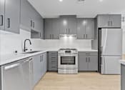 Thumbnail 105 of 119 - A modern kitchen with stainless steel appliances and grey cabinets.