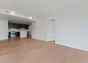 Thumbnail 98 of 119 - A large empty room with wooden floors and a kitchen area in the background.