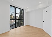 Thumbnail 35 of 119 - A room with a sliding glass door and wooden flooring.