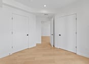 Thumbnail 42 of 119 - A long hallway with white doors and wooden floors.