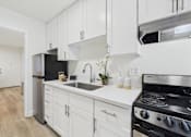 Thumbnail 18 of 79 - A modern kitchen with white cabinets and a black stove top oven.