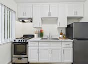 Thumbnail 7 of 79 - A kitchen with white cabinets and a black refrigerator.