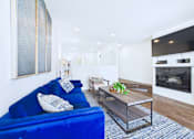 Thumbnail 23 of 49 - A living room with a blue couch and a television.