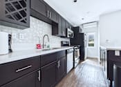 Thumbnail 18 of 49 - A kitchen with black cabinets and a white counter.