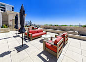 Thumbnail 54 of 56 - A patio with red couches and black umbrellas overlooking a waterway.