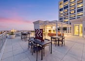 Thumbnail 49 of 56 - A patio with a table and chairs overlooking a cityscape at dusk.