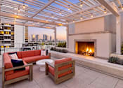 Thumbnail 48 of 56 - A patio with a fireplace and a view of the city.