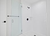 Thumbnail 116 of 119 - A white bathroom with a glass shower door and a drain in the floor.