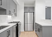 Thumbnail 61 of 119 - A modern kitchen with a stainless steel refrigerator and black and white cabinets.