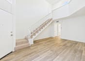 Thumbnail 17 of 115 - A white interior with a wooden staircase.