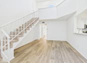 Thumbnail 20 of 115 - A white interior with a staircase and a kitchen area.