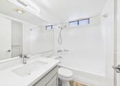 Thumbnail 23 of 115 - A white bathroom with a toilet, sink, and shower.