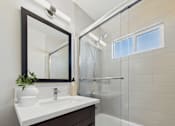 Thumbnail 9 of 49 - A bathroom with a sink, mirror, and shower.