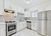 Thumbnail 42 of 49 - A kitchen with white cabinets and a stainless steel refrigerator.
